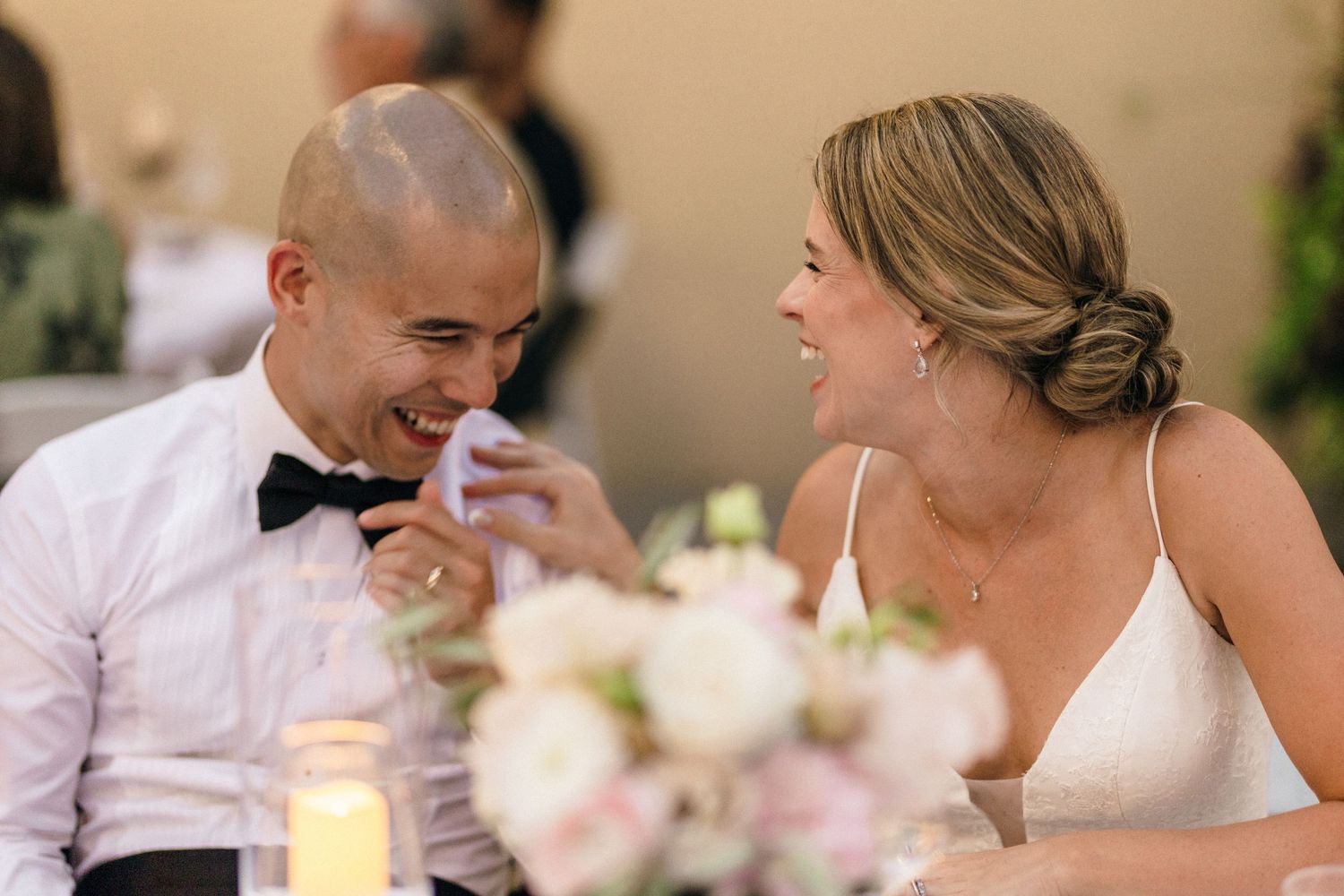 Candlelit wedding reception with soft focus on table settings and decor.