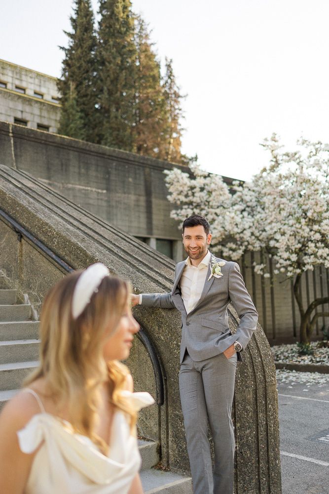 A wedding photo on concrete steps with blooming cherry trees in the background.