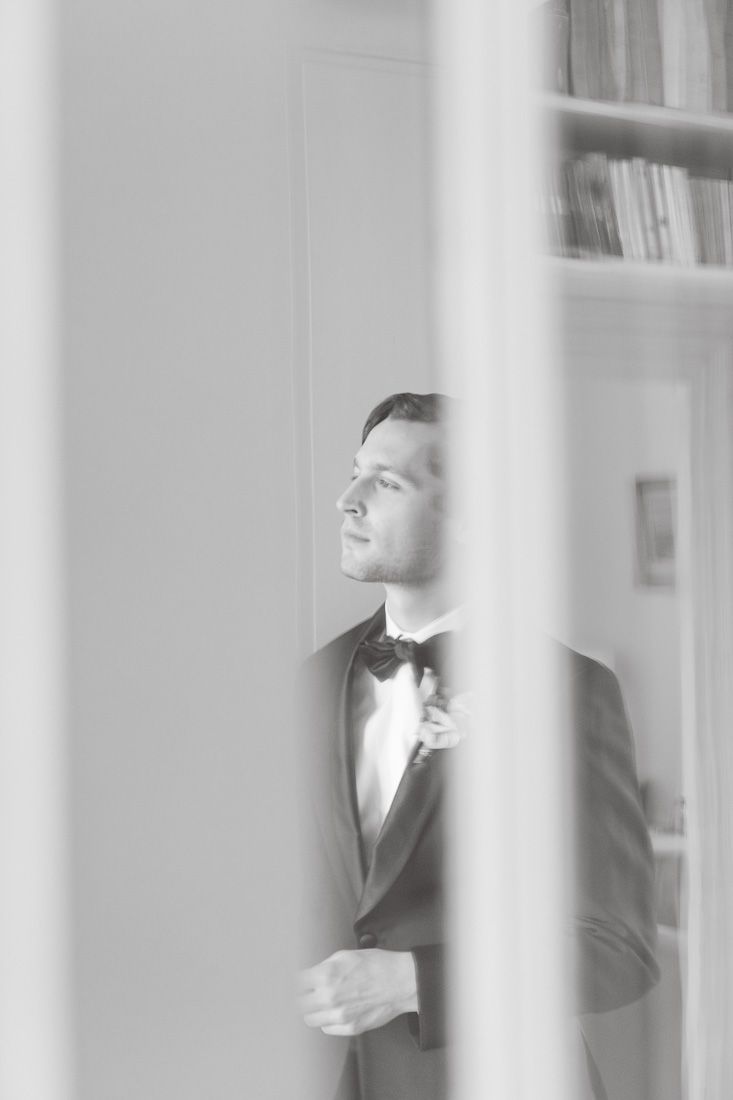 Artistic black and white portrait through doorway in elegant interior setting.