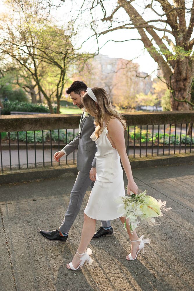 Couple in wedding attire walks together on path during golden hour.