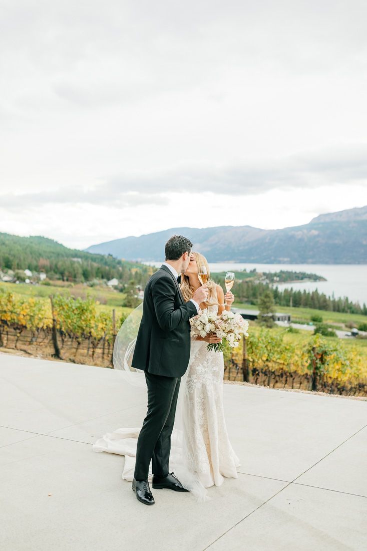 Couple shares champagne while enjoying mountain and vineyard views at their wedding.