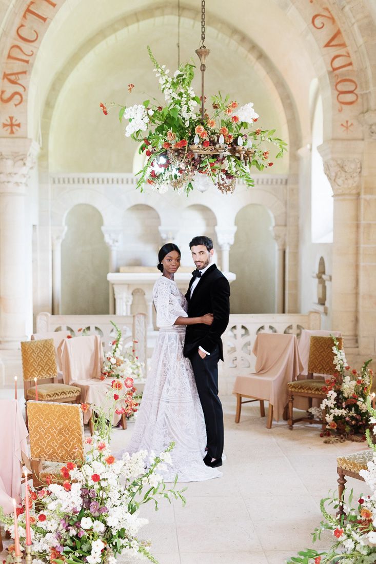 Romantic wedding ceremony space with hanging floral chandelier and architectural arches.