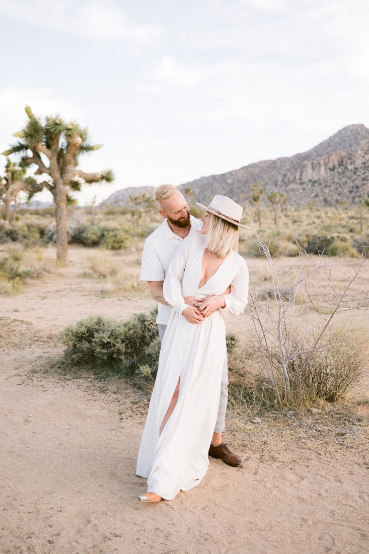 Romantic desert embrace captured among Joshua trees and mountain scenery.