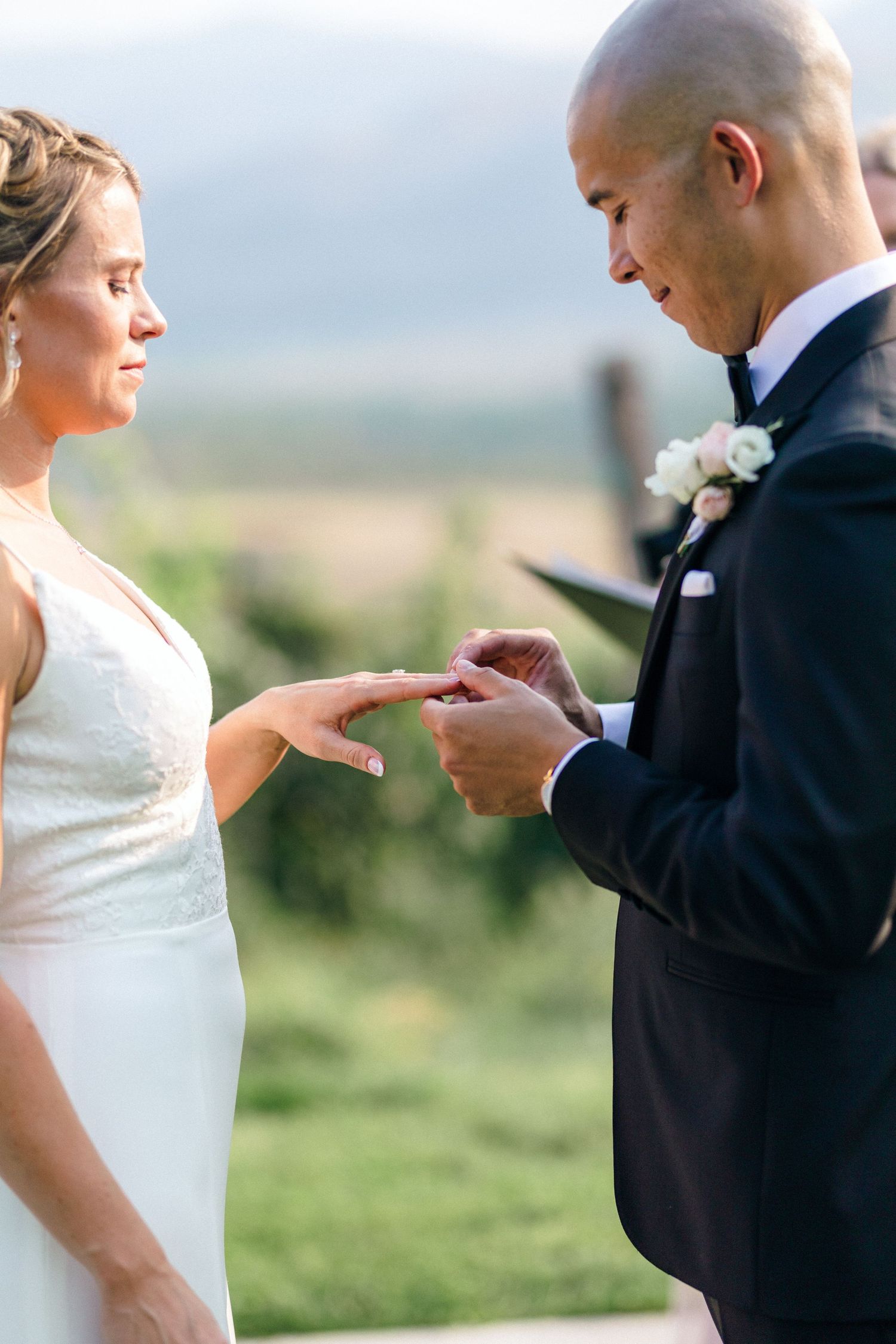 Wedding couple exchanging rings during outdoor ceremony.