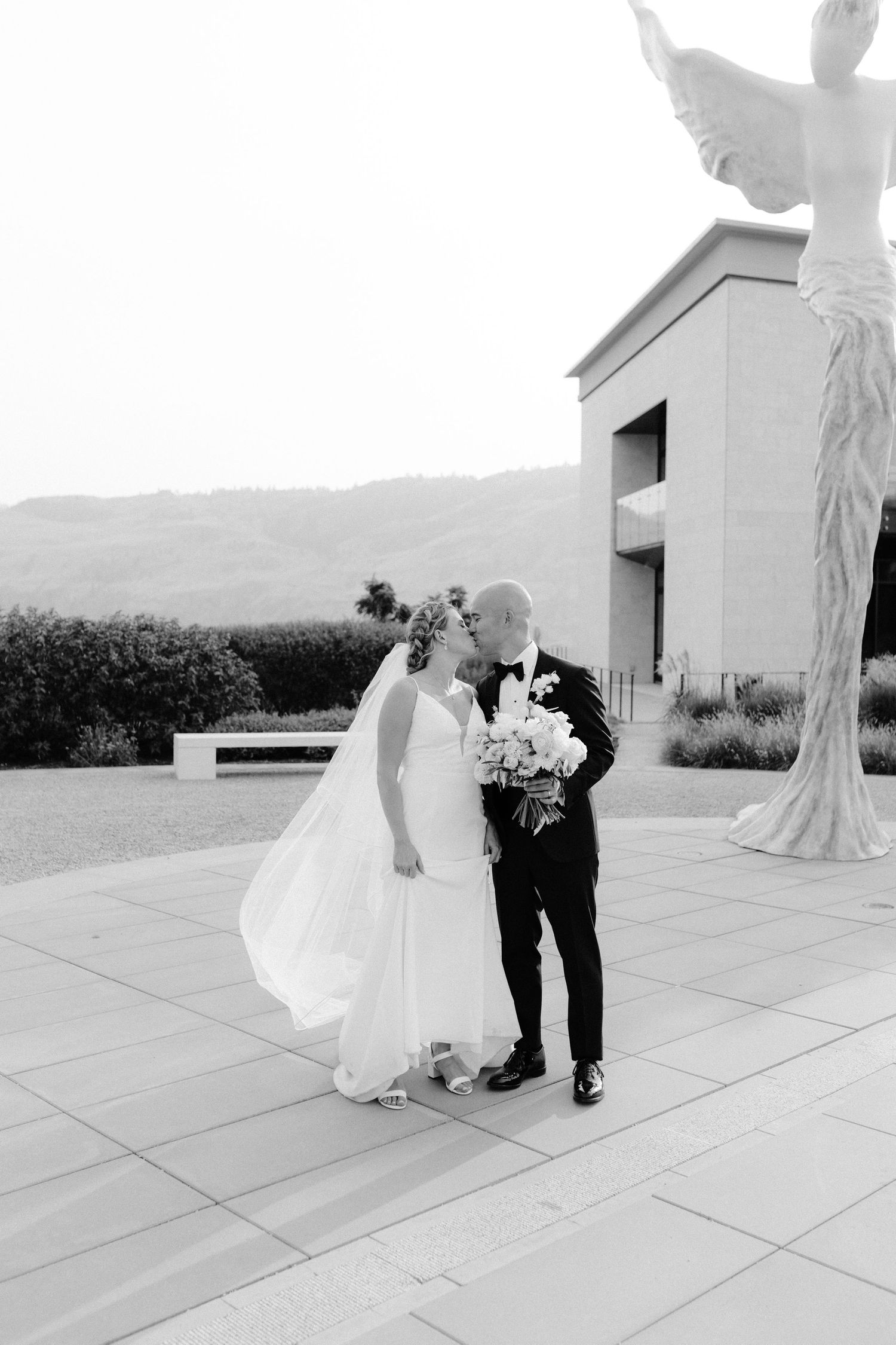 Black and white wedding photos of a couple on a paved terrace with mountain views.