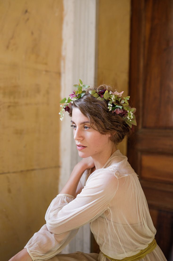 Soft natural light portrait featuring delicate floral crown and flowing cream-colored dress.