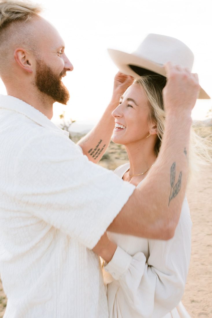 Playful desert engagement photo with couple laughing and sharing joyful moment.