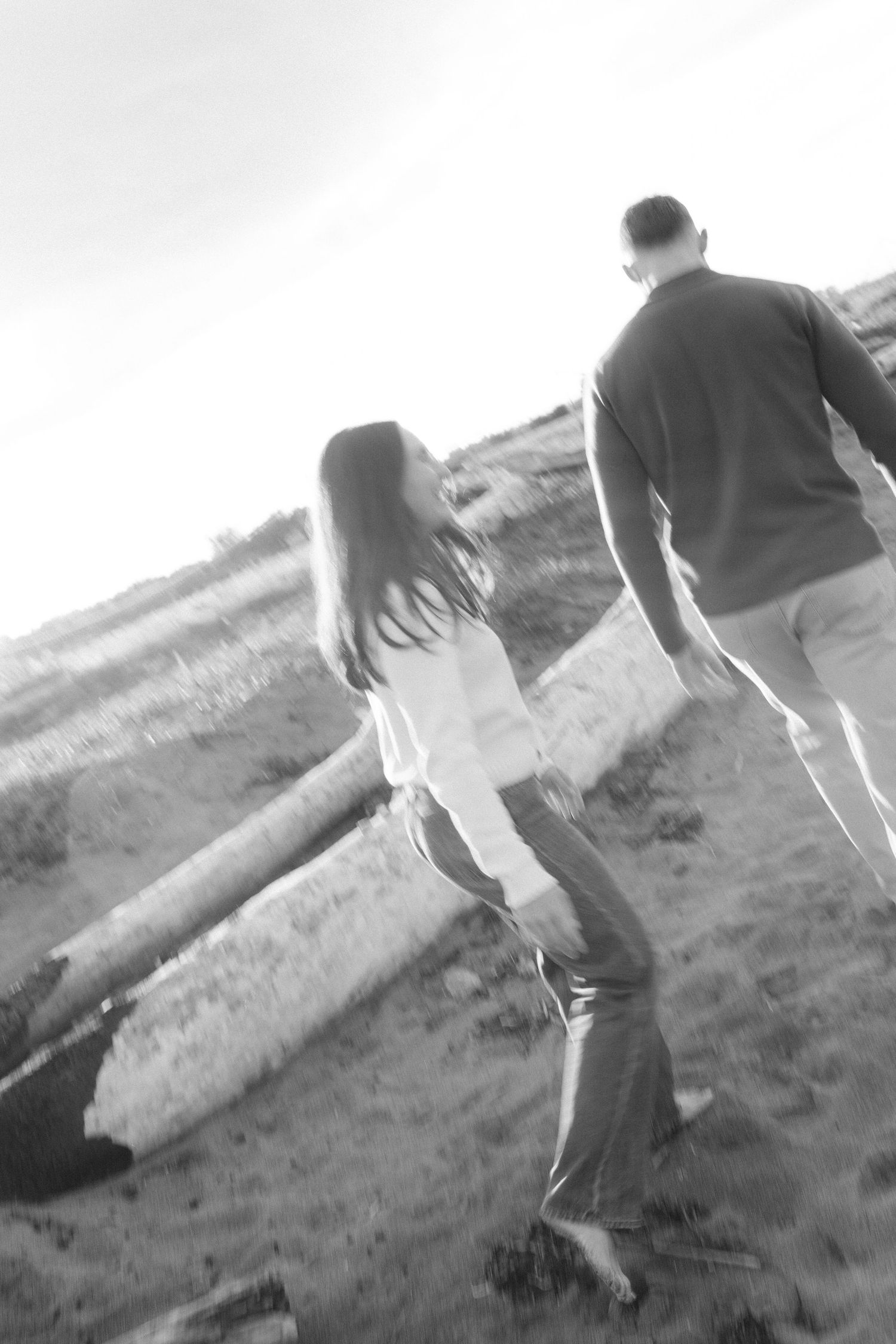 Two people walking on hillside slope in black and white artistic photograph.