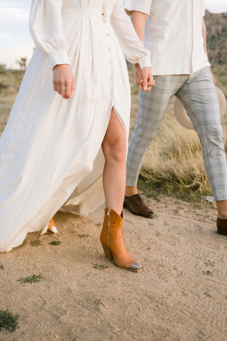 Close-up of couple's legs showing plaid pants and white dress with brown boots.