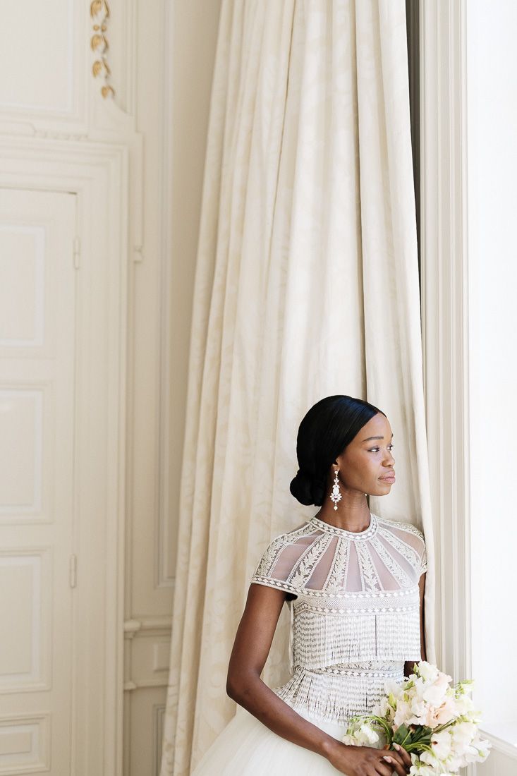 Elegant bridal portrait featuring a tea-length wedding dress with detailed beading and delicate cap sleeves.