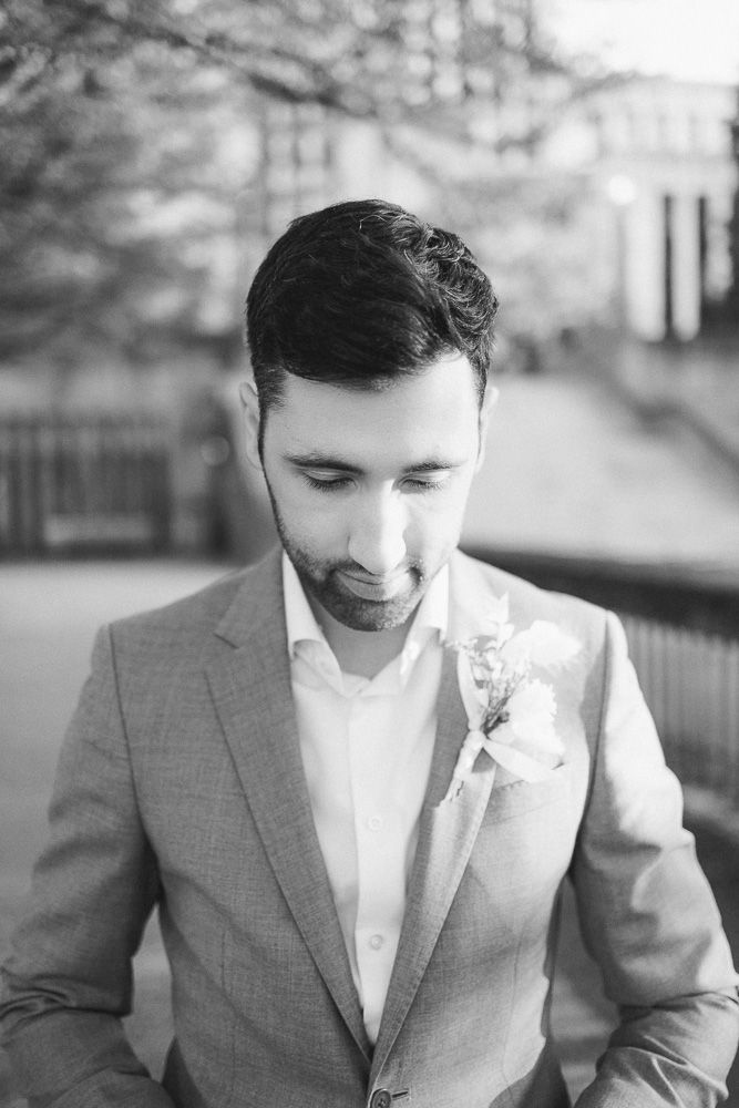 Black and white portrait showing details of a formal suit and boutonniere.