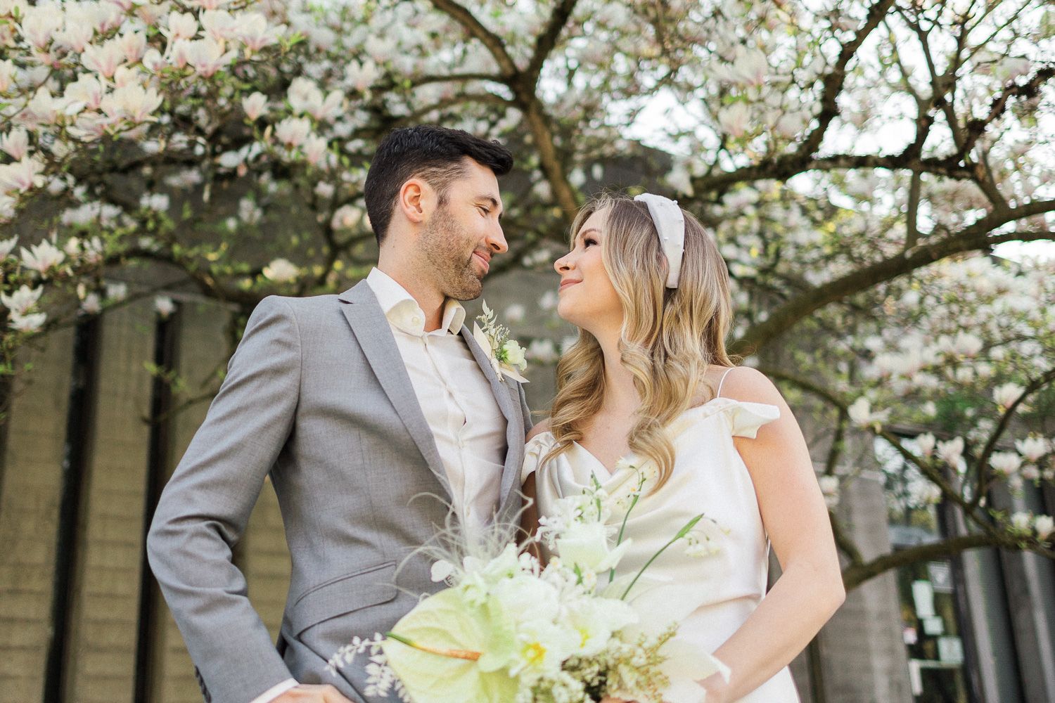 Intimate moment between newlyweds beneath blooming spring trees.