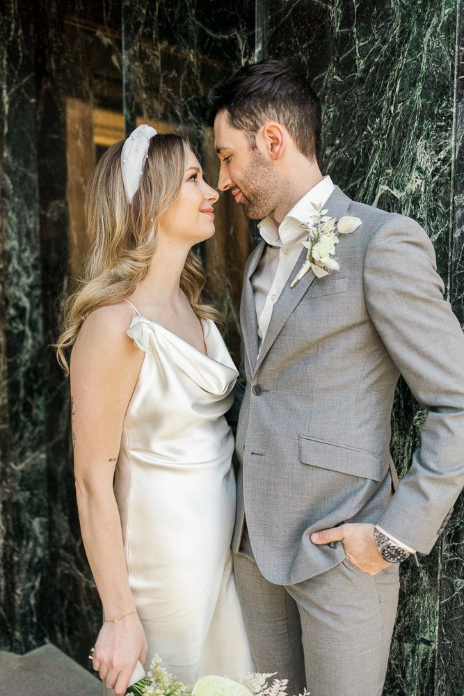 Intimate moment between couple in wedding attire against dark marble backdrop.