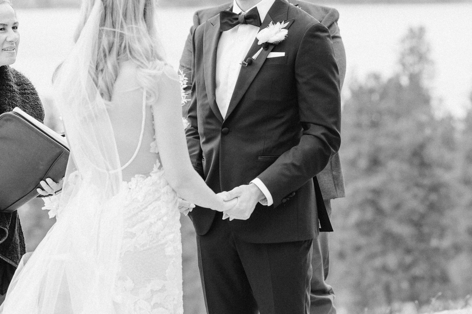 A black and white photo captures an intimate moment during outdoor wedding vows.