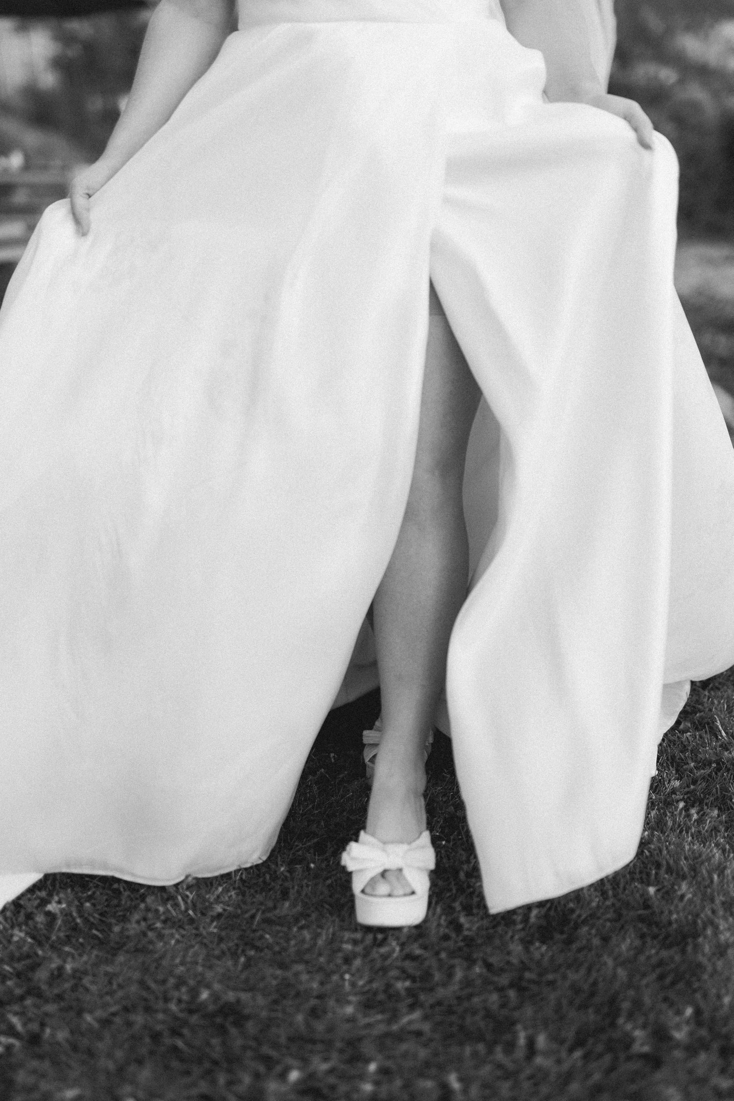 The hem of a white wedding dress sweeping across dark grass in a series of progressive motion shots.