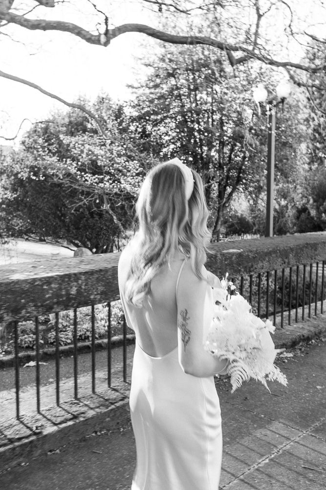 Black and white photo shows back detail of wedding dress against garden backdrop.