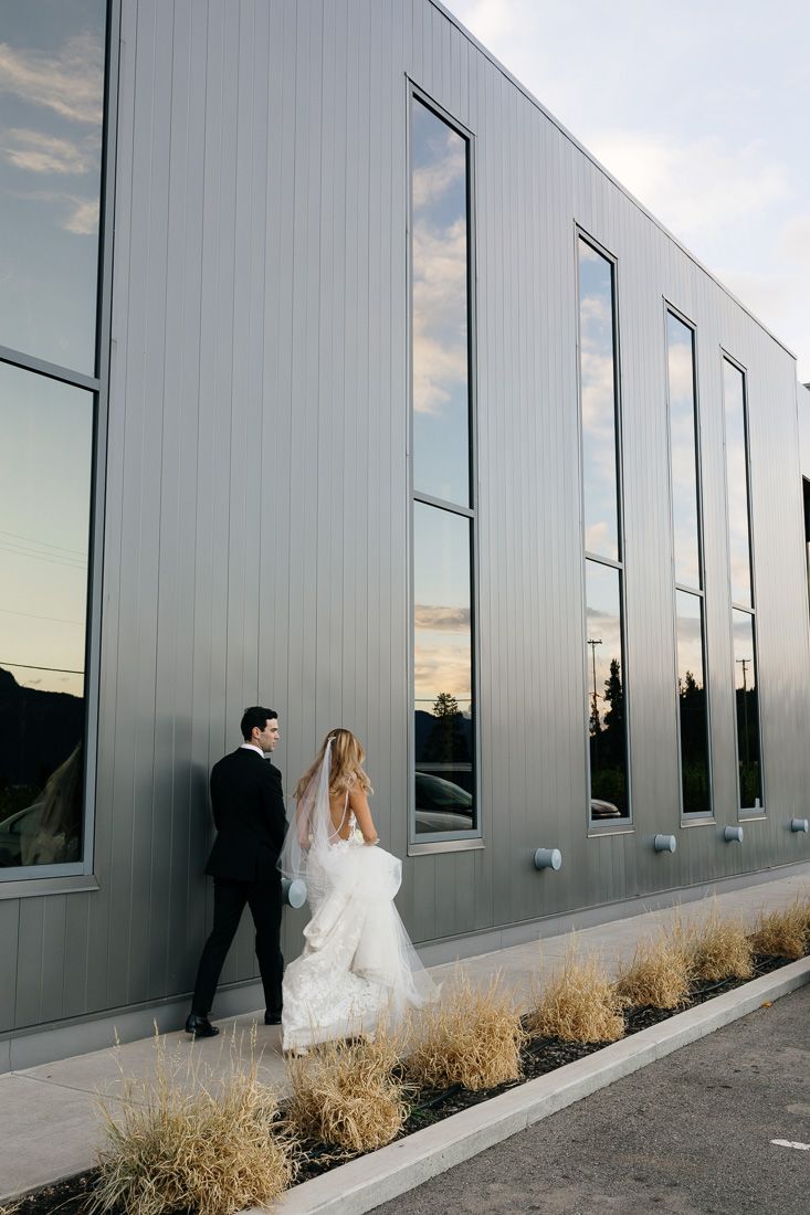 Modern architectural wedding photo with reflective windows and metal siding.