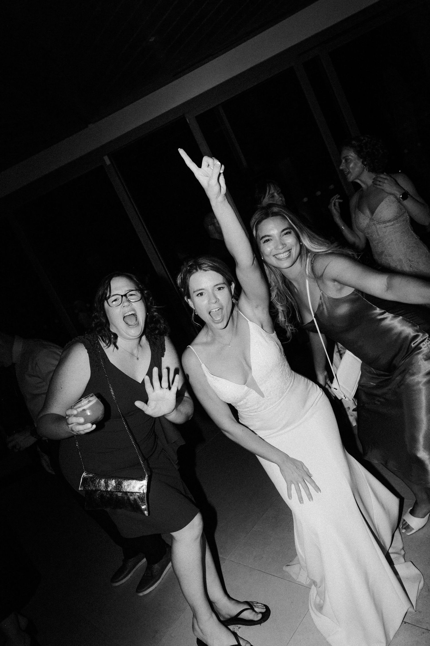 Black and white candid shots of wedding guests dancing and celebrating at reception.