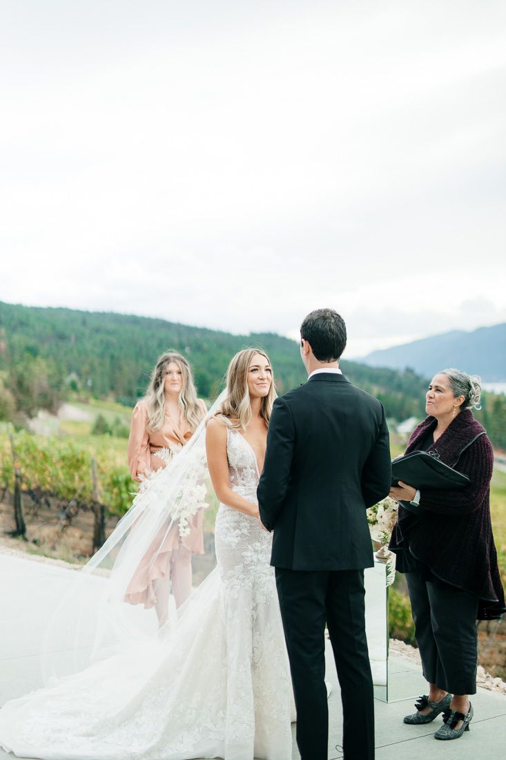 An outdoor wedding ceremony with mountain views and pampas grass decorations.