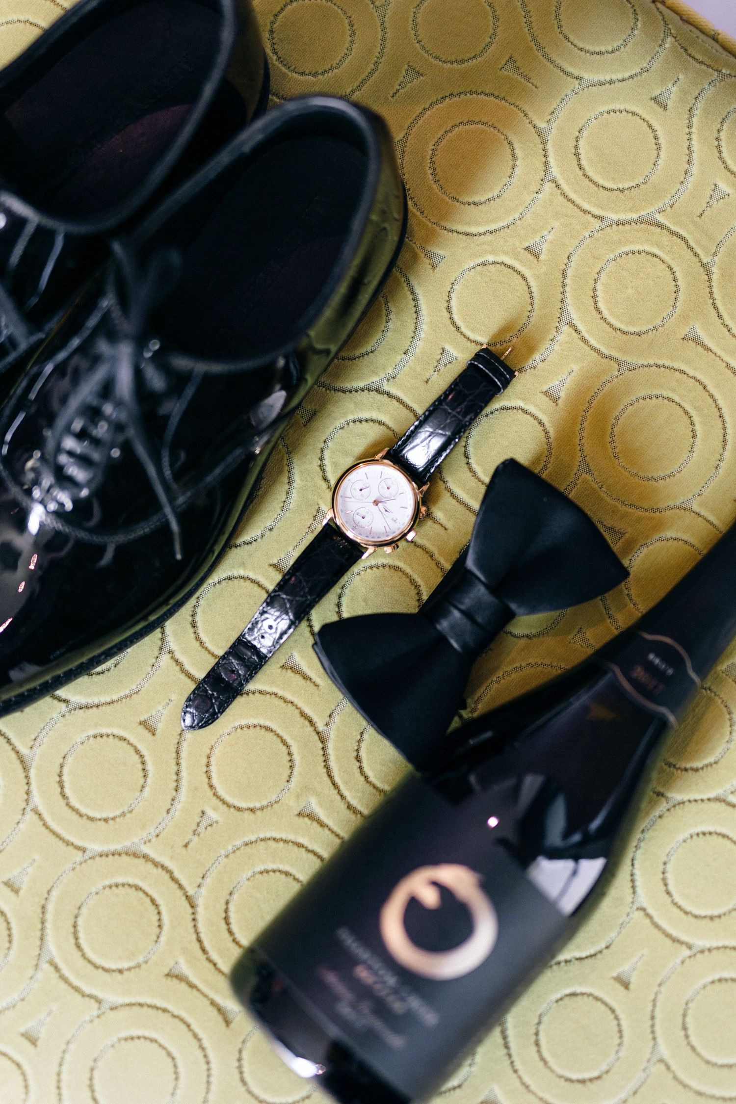 Close-up shots of formal black dress shoes and watches arranged on a textured gold surface.