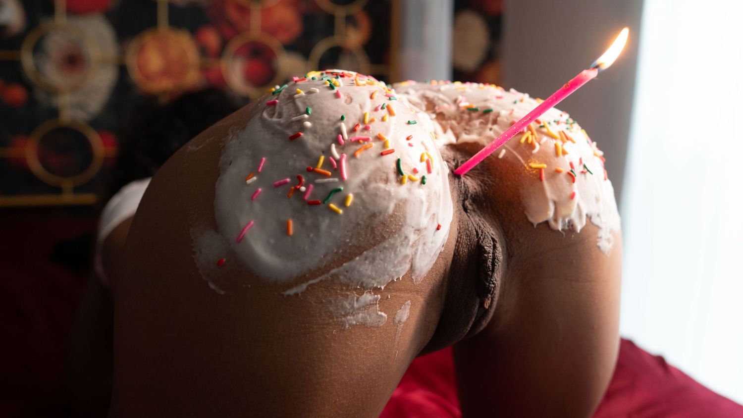 A chocolate birthday cake with lit candle and sprinkles being cut into slices in progressive stages.