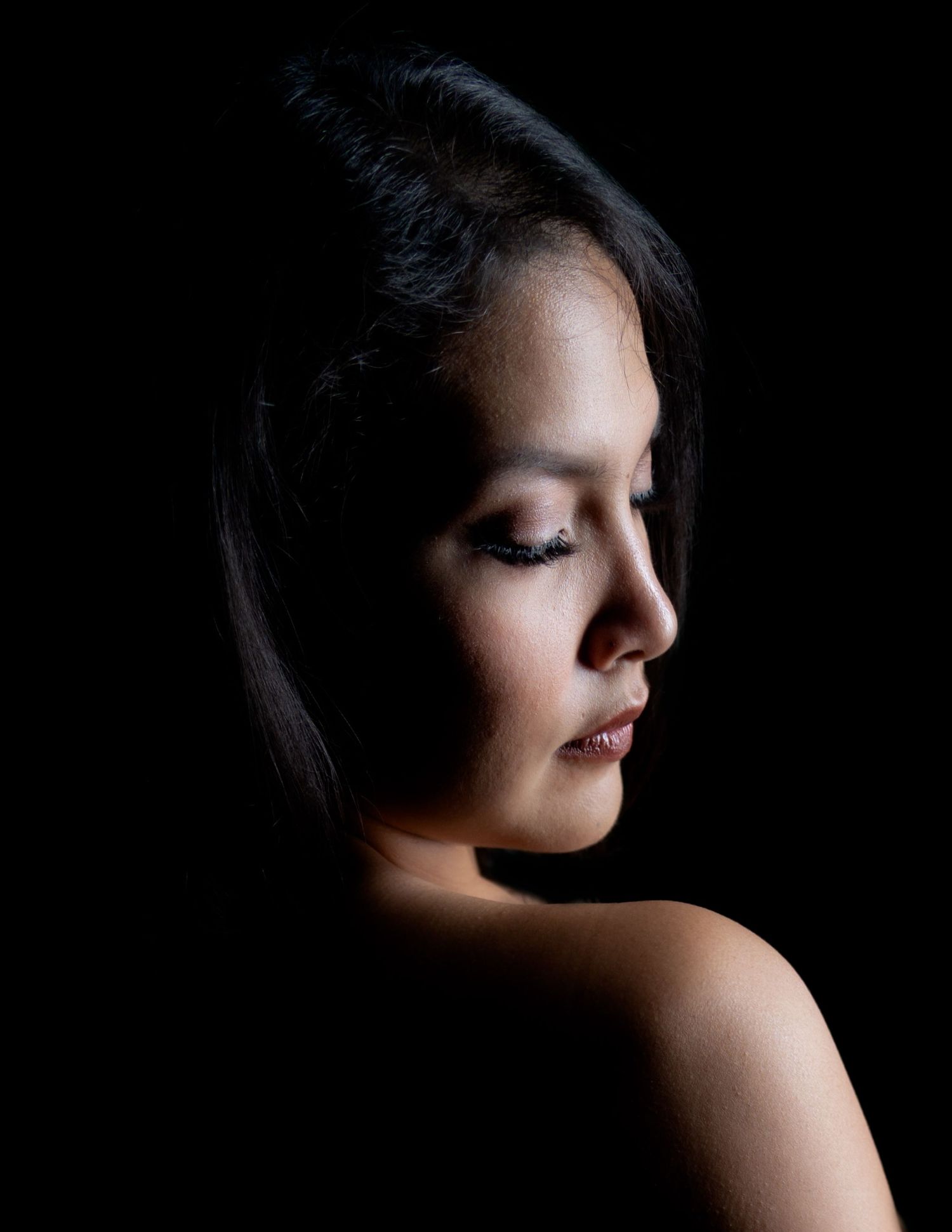 Dramatic side profile portrait in black and white with soft lighting highlighting features.