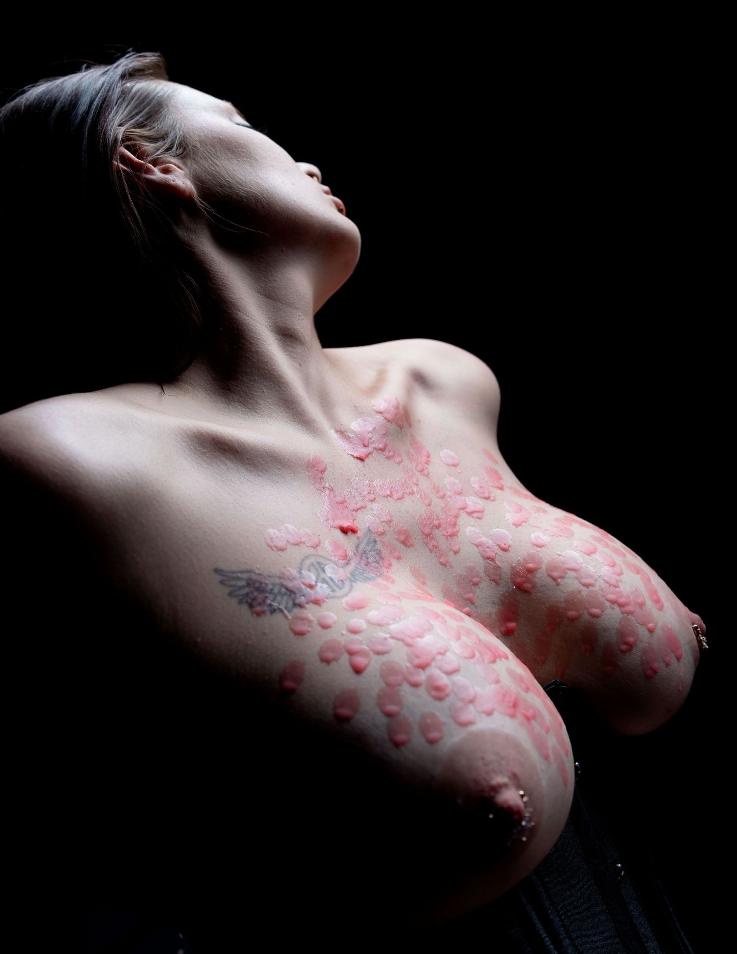 Artistic black and white photo series showing skin decorated with pink kiss marks in dramatic lighting.