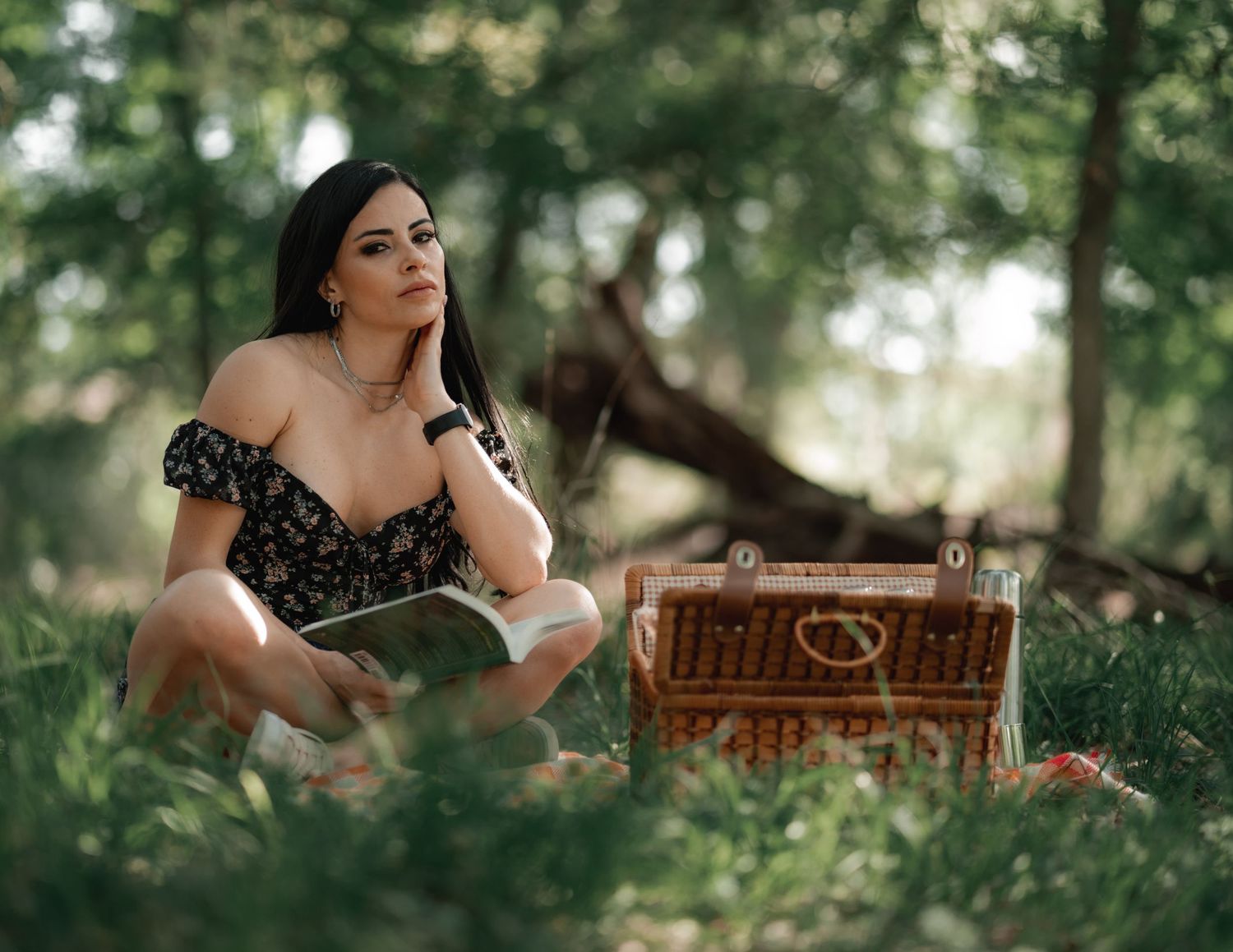 Vintage-inspired outdoor picnic scene with wicker basket in summer forest setting.