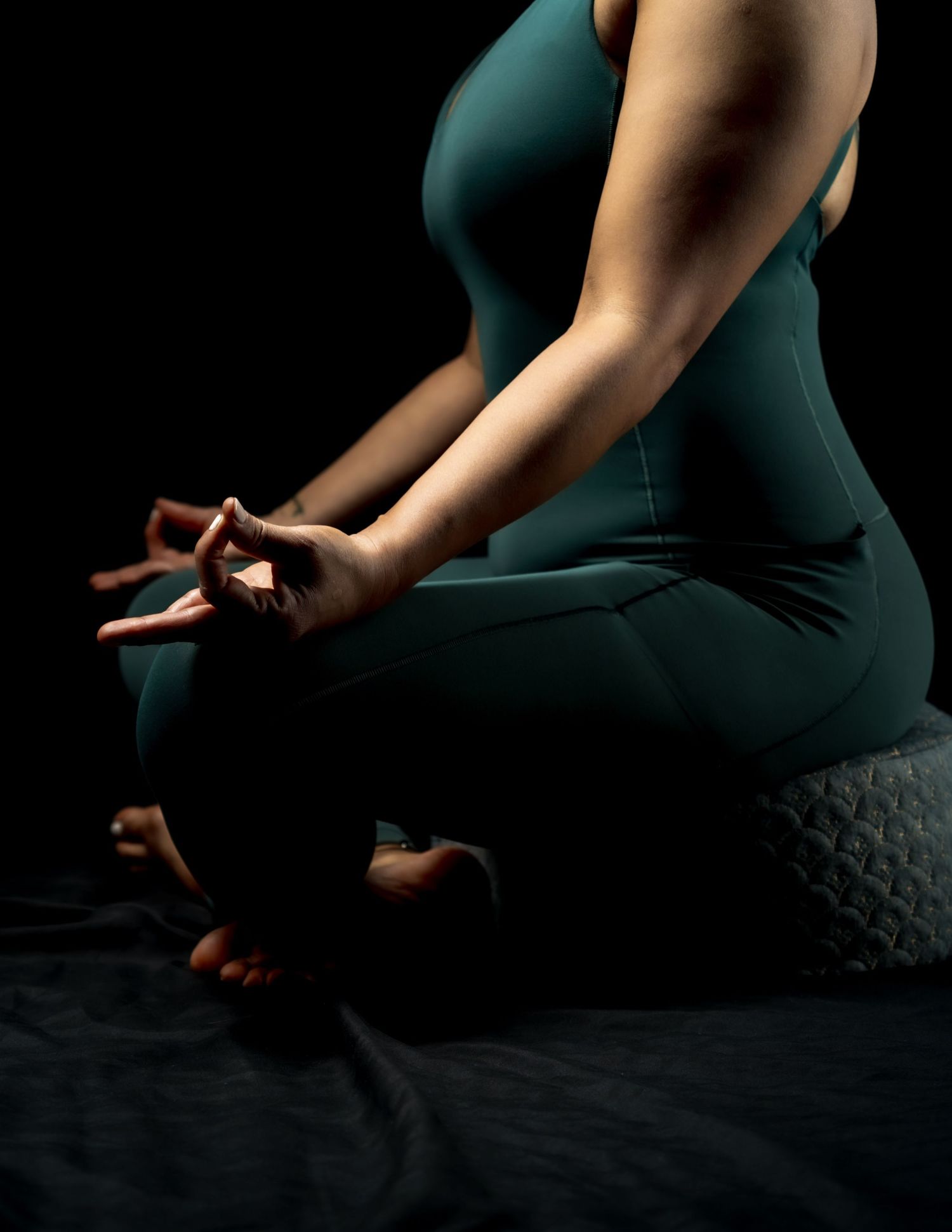 Silhouetted hands performing meditation mudra gestures against dark background in dramatic lighting.