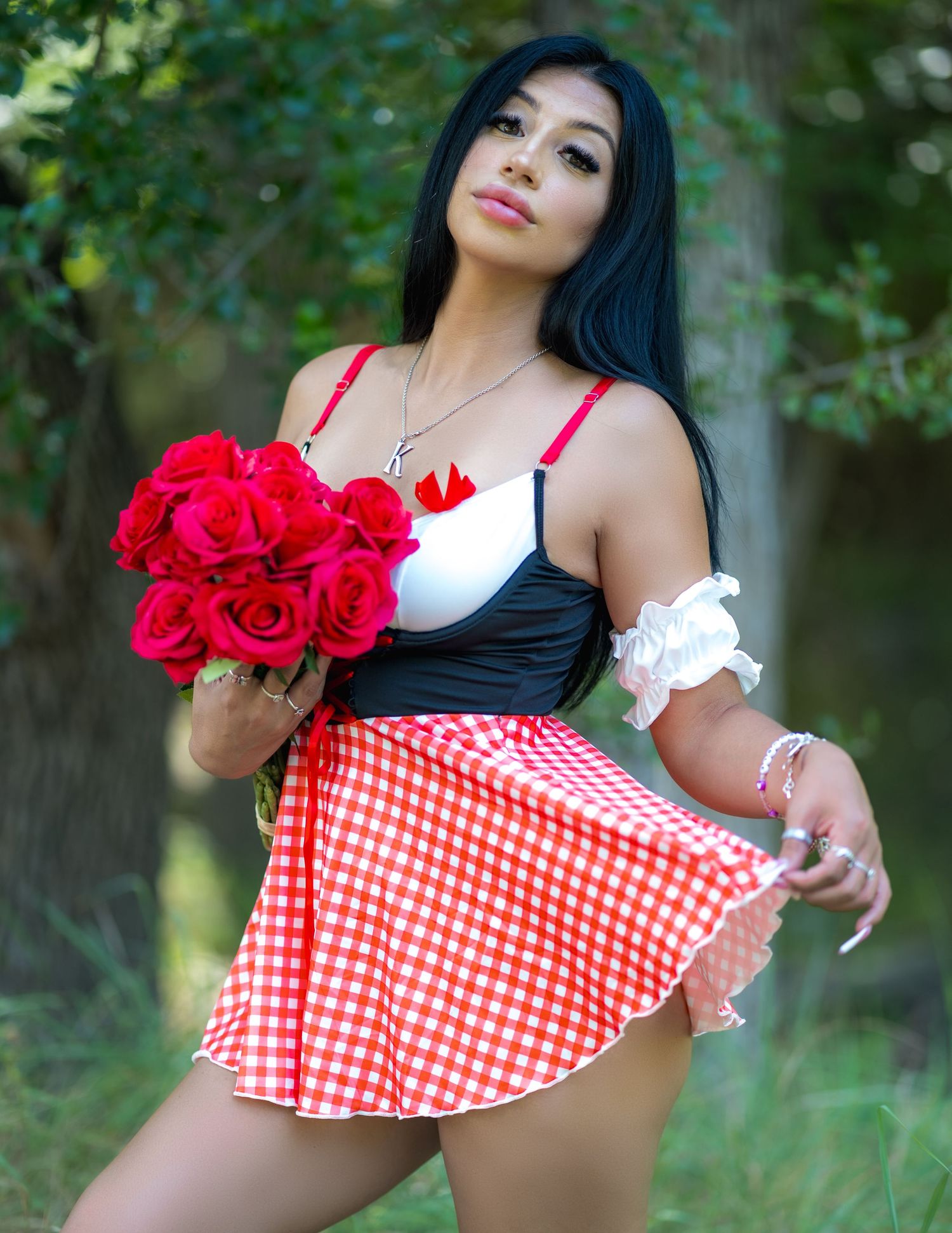 A red and white gingham patterned dress with floral accents photographed in an outdoor garden setting.