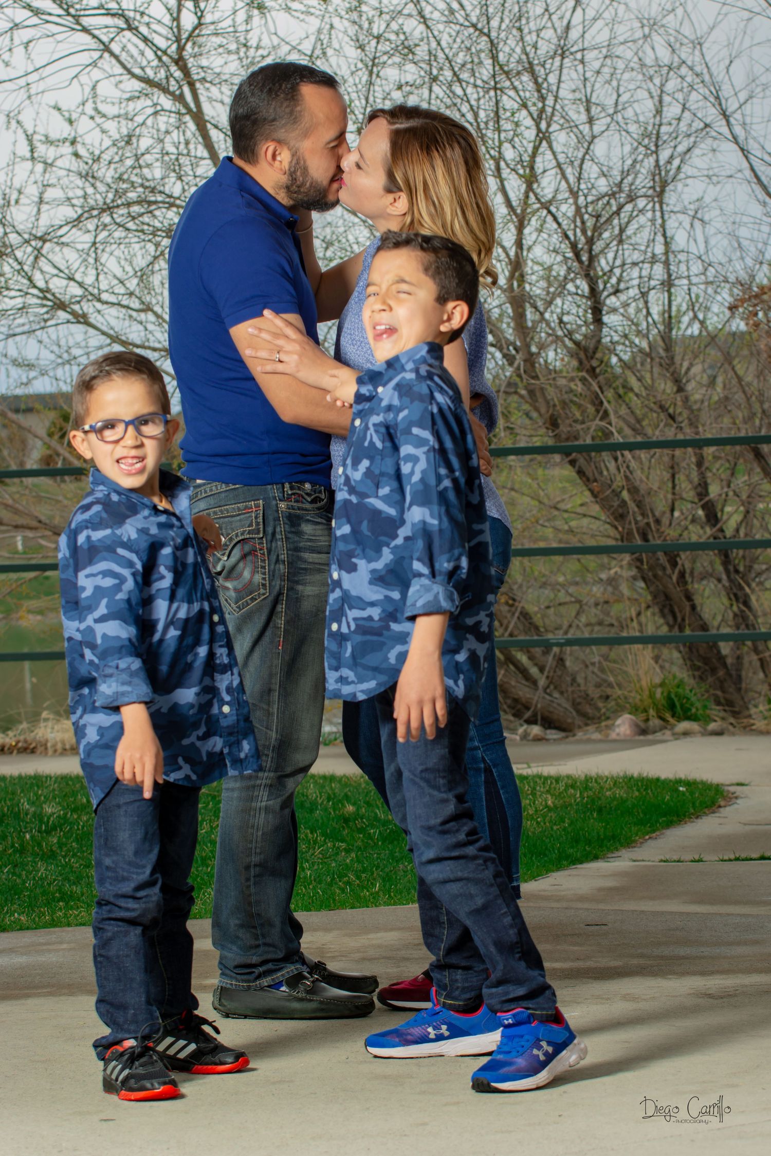 Happy family of four in matching blue outfits share a loving moment outdoors in spring.