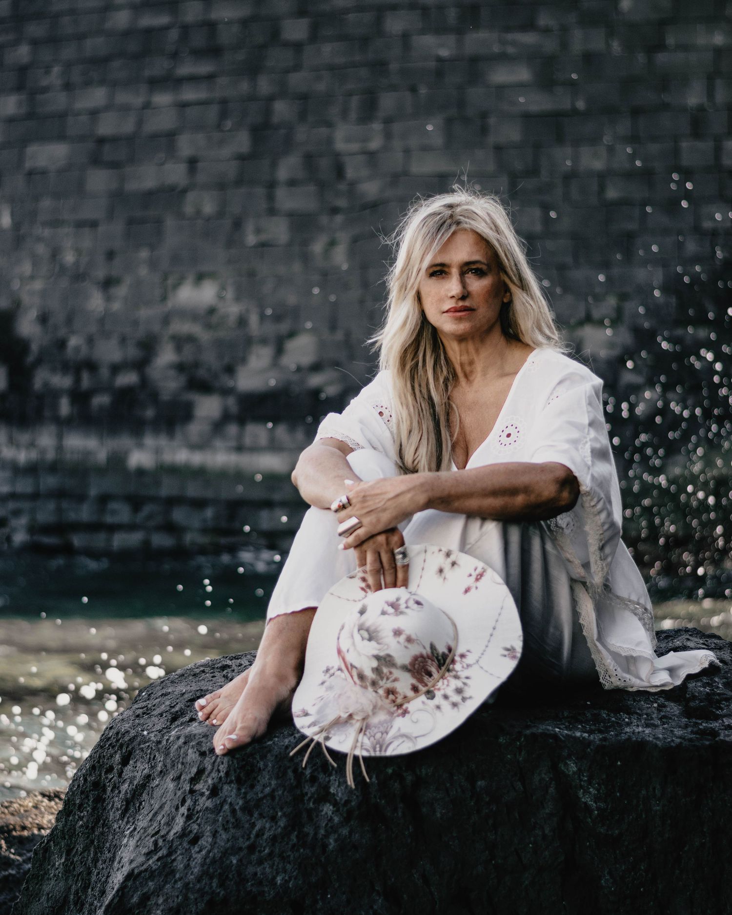 Künstlerisches Outdoor-Portrait einer Frau sitzend auf einem Felsen, Sedcard Fotografie für Schauspieler in nature