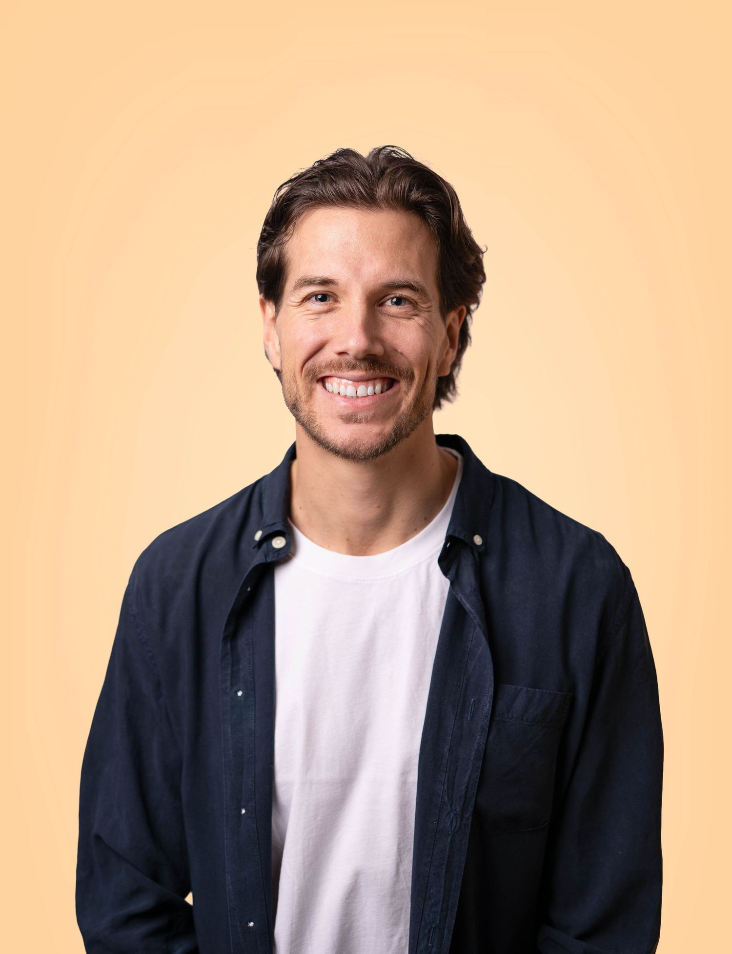 Professioneller Headshot eines Schauspielers vor warmem Hintergrund für Sedcards und Castings in Chur.