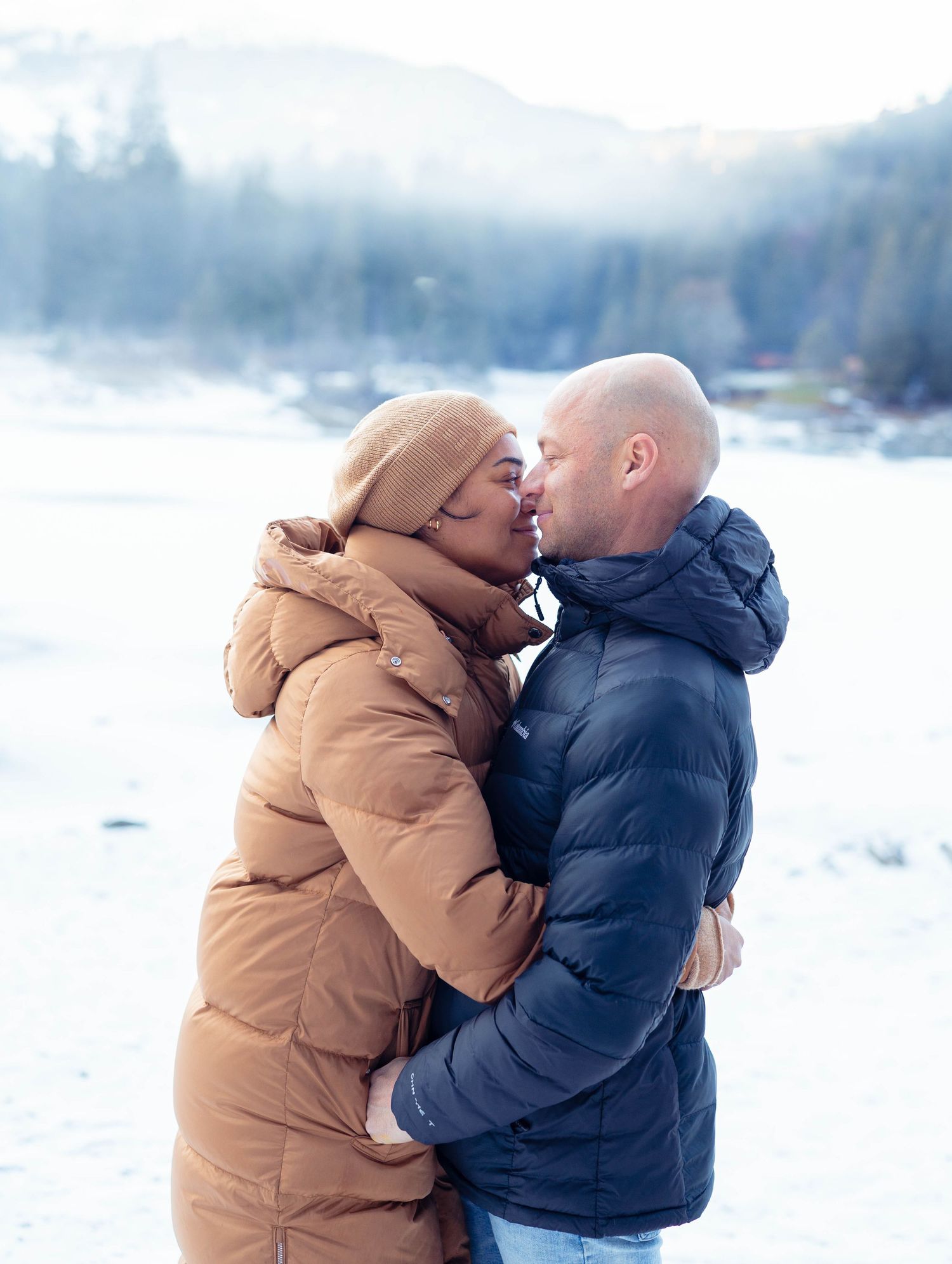 Romantischer Kuss eines Paares im Schnee, emotionales Paarportrait am winterlichen Caumasee in Flims.