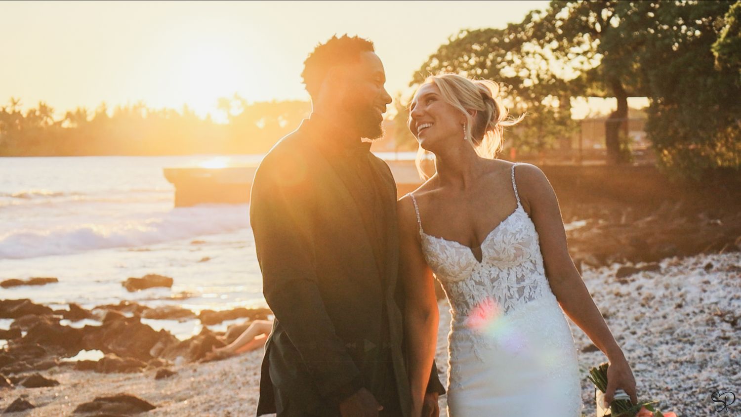A bride looks adoringly into the eyes of the groom with the sunset behind in Kona, Hawai'i.