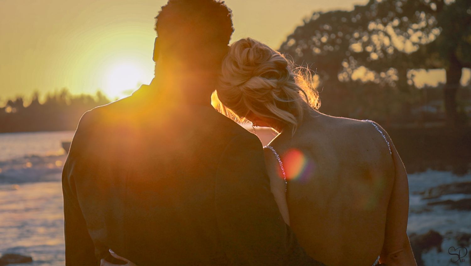 A bride leans on her groom's shoulder, looking off into the sunset at Kona, Hawai'i.
