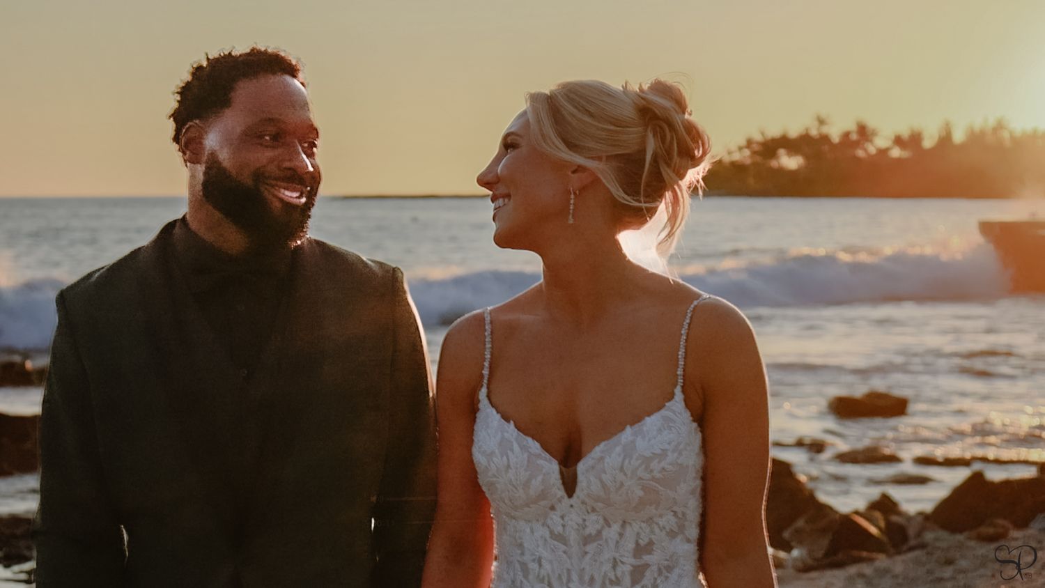 A bride looks adoringly into the eyes of the groom with the sunset behind in Kona, Hawai'i.
