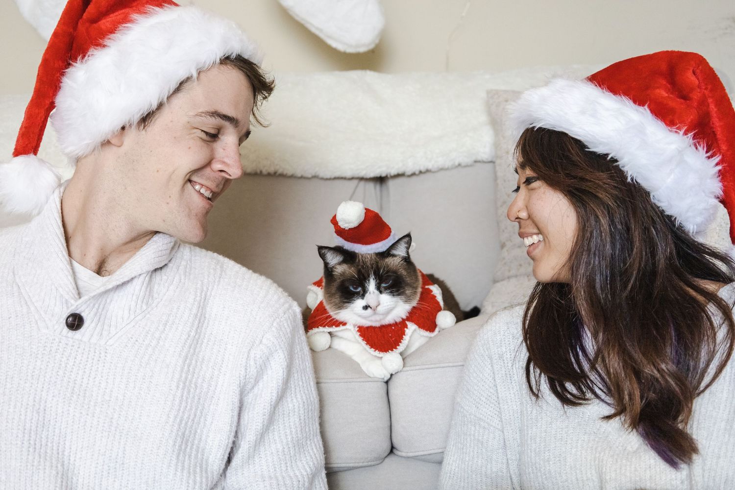A picture by Sara Pang (MSK Productions) of a couple sitting and looking at a cat on a couch in Christmas holiday garb.