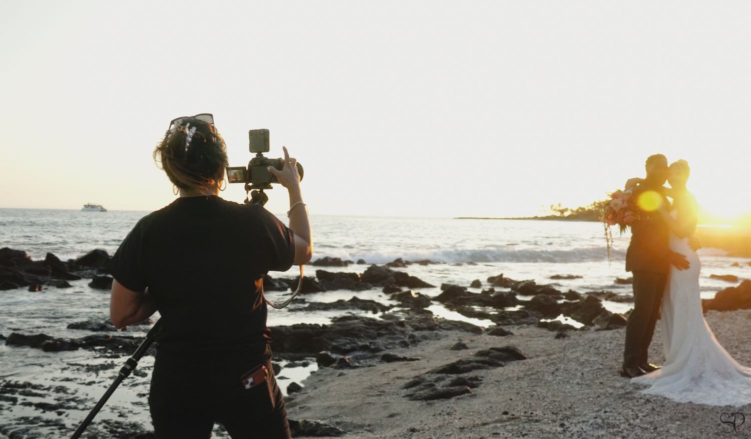 A photo of videographer Sara Pang (MSK Productions) as she videos a wedding couple on the beach of Papa Kona's in Kona, Hawai'i.