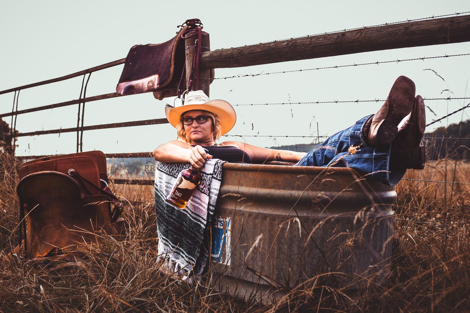 A punchy, western style portrait of a cowgirl hanging out in a water trough.