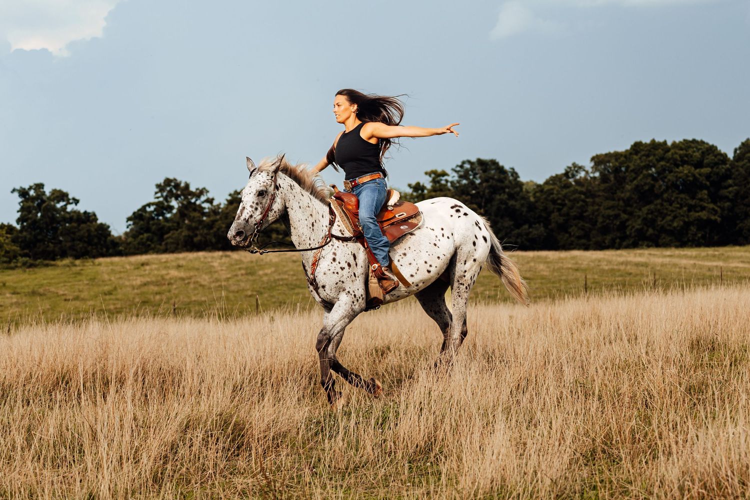 A free spirited woman riding a horse hands-free.