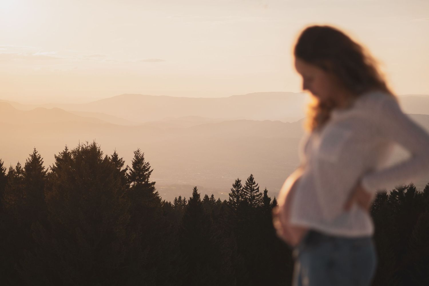 Femme enceinte lors d'une séance grossesse en montagne en hiver au soleil couchant.