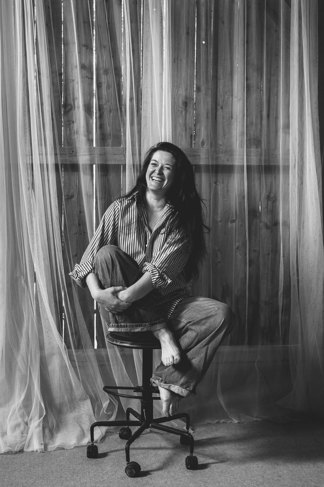 Portrait de femme souriante et décontractée en noir et blanc dans une grange