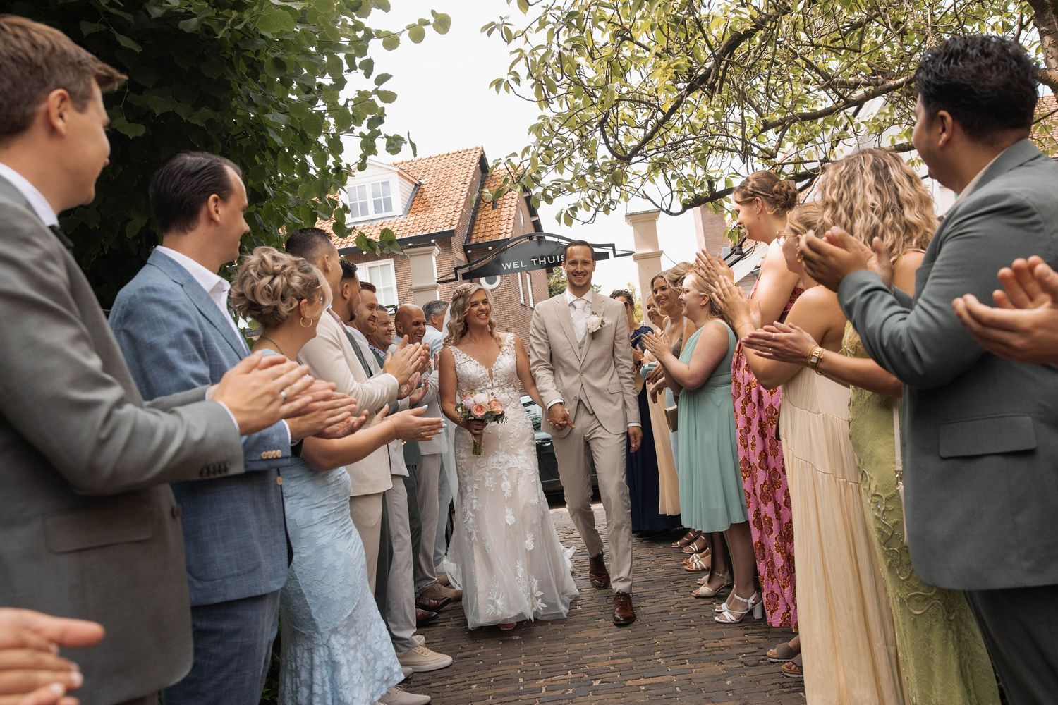 Bride and groom walk through cheering guests at outdoor wedding ceremony celebration.