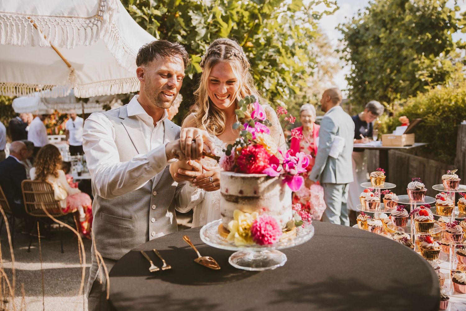 Guests enjoy an outdoor garden party with cake and refreshments on a sunny summer afternoon.