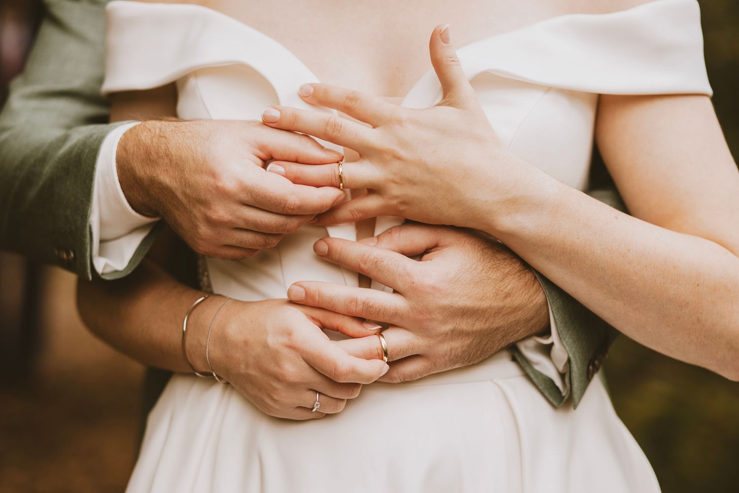 Close-up of hands and wedding attire details in natural lighting.