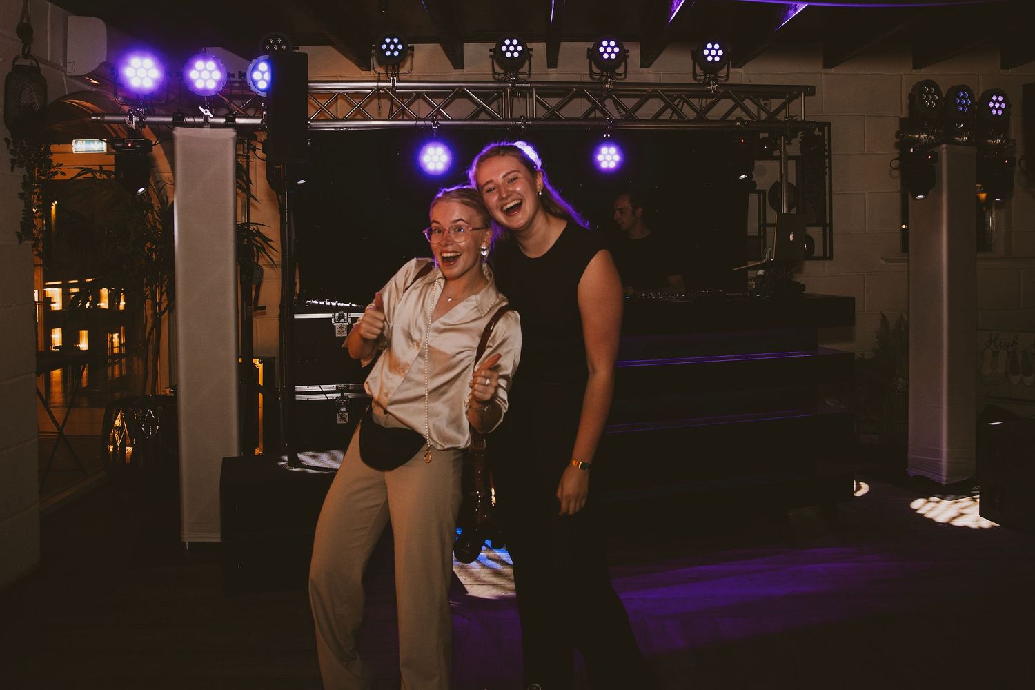 Dark reception venue with purple stage lighting and dance floor setup.