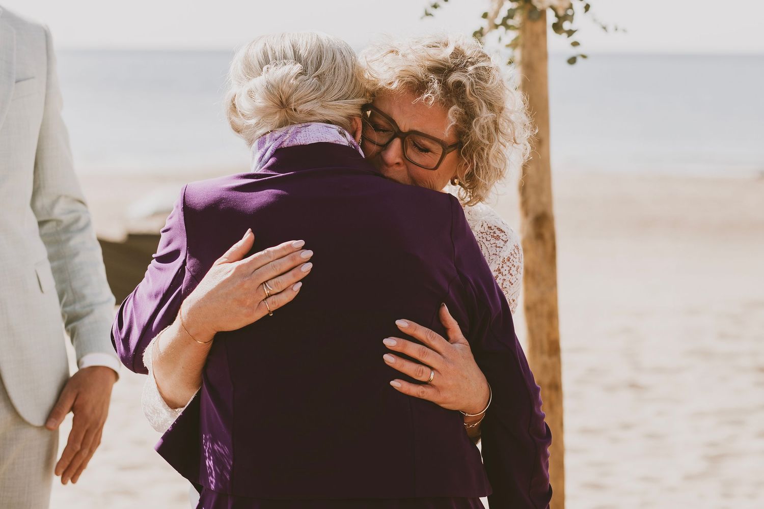 Emotionele omhelzing vastgelegd tijdens een huwelijk op het strand.