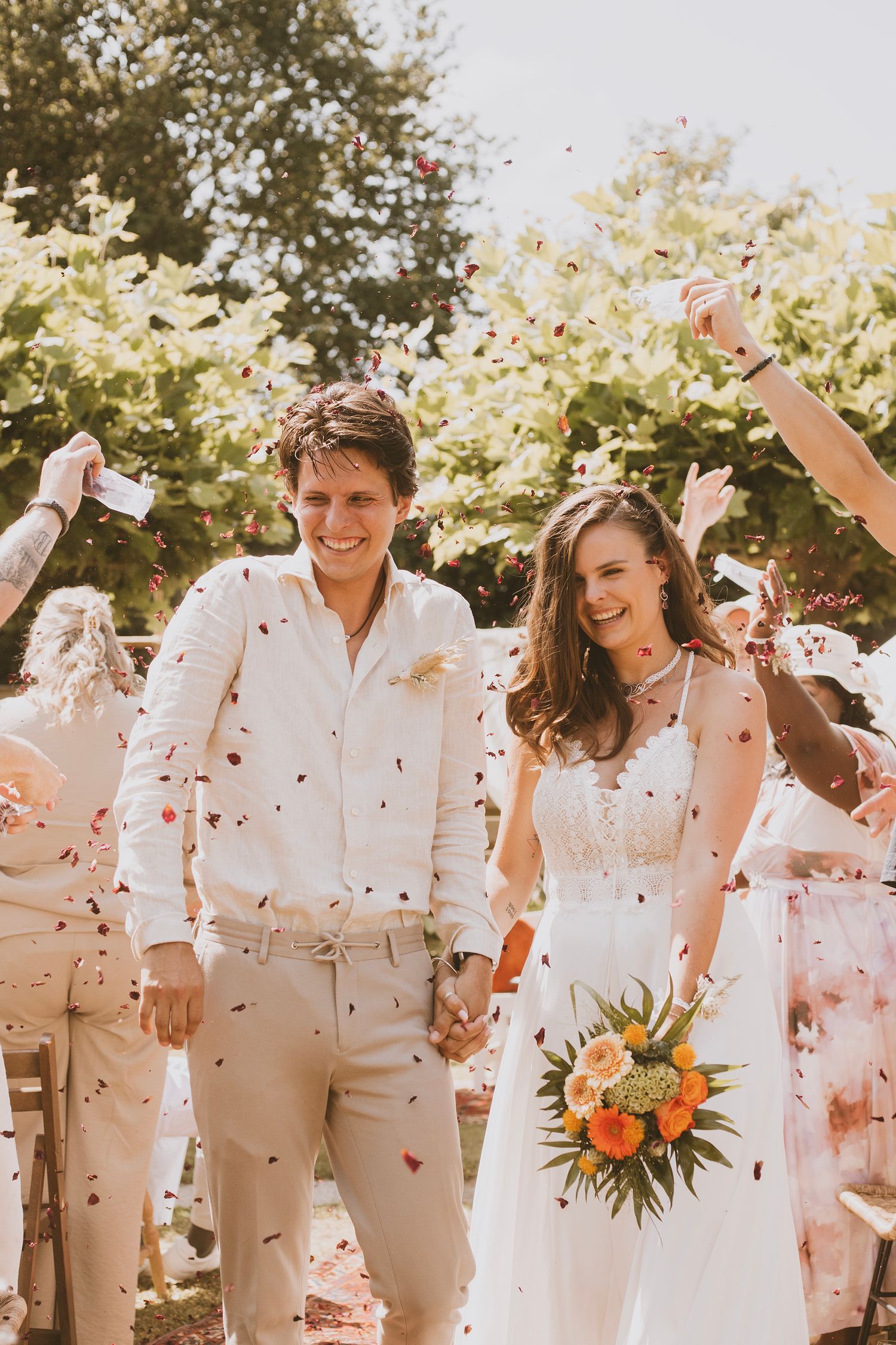 A joyful wedding celebration with confetti falling on the newlyweds in a garden setting.