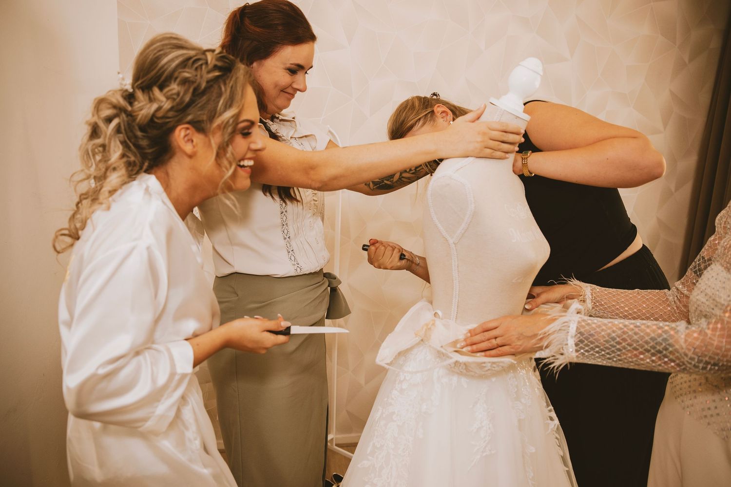 Wedding party helps adjust a bride's dress during final preparations before the ceremony.